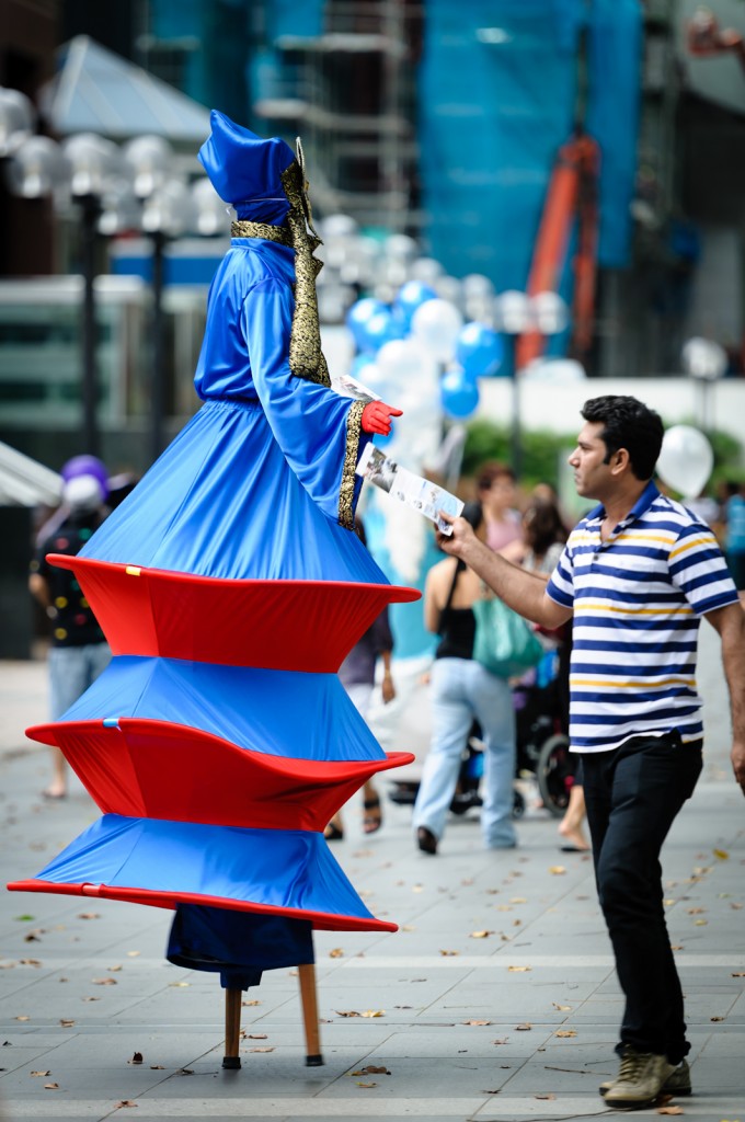 Street photography - man taking a flyer from a person on stilts