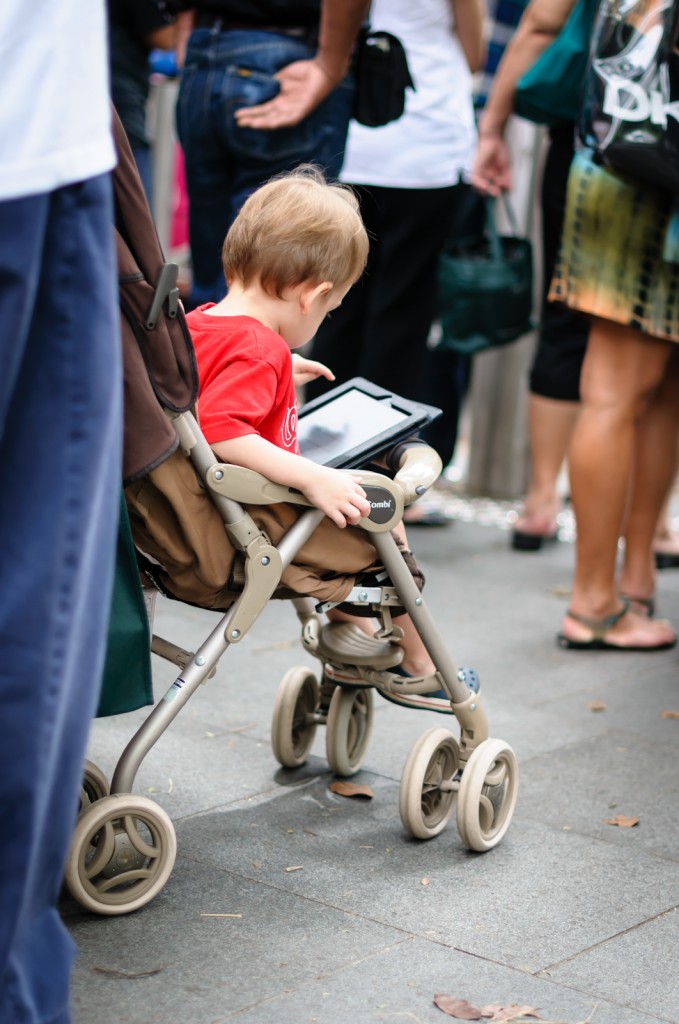 Street photography - child in pram playing with iPad