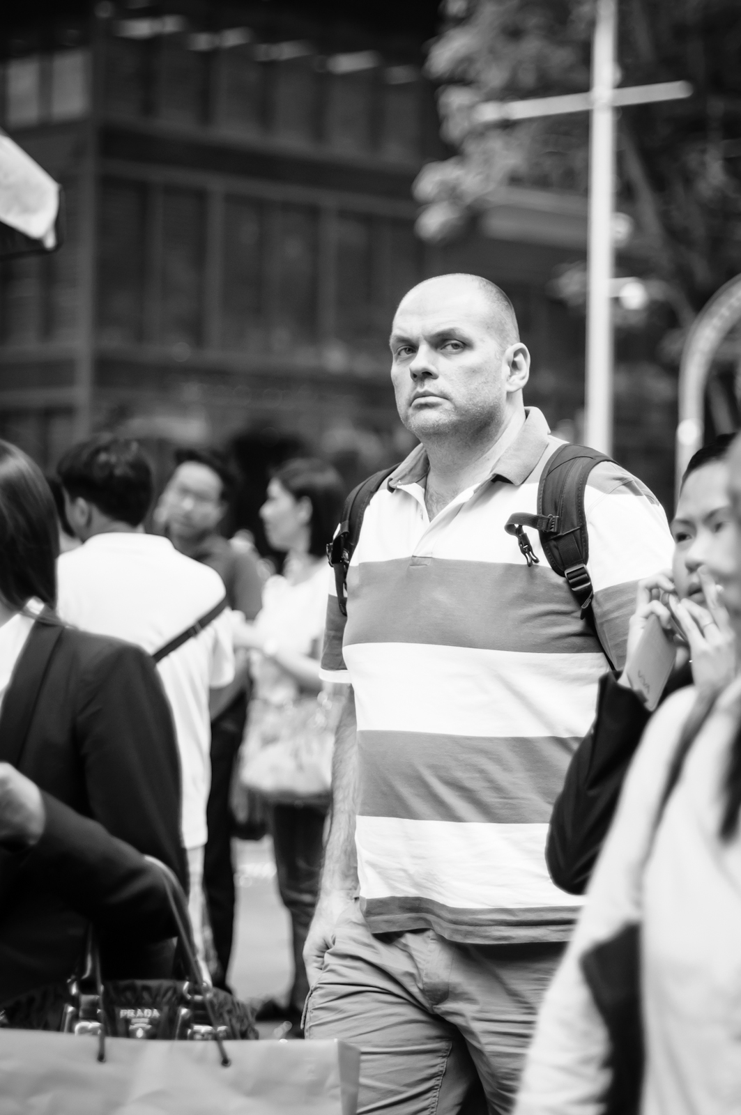 Street photography - man in broad-striped polo t-shirt looking at the camera