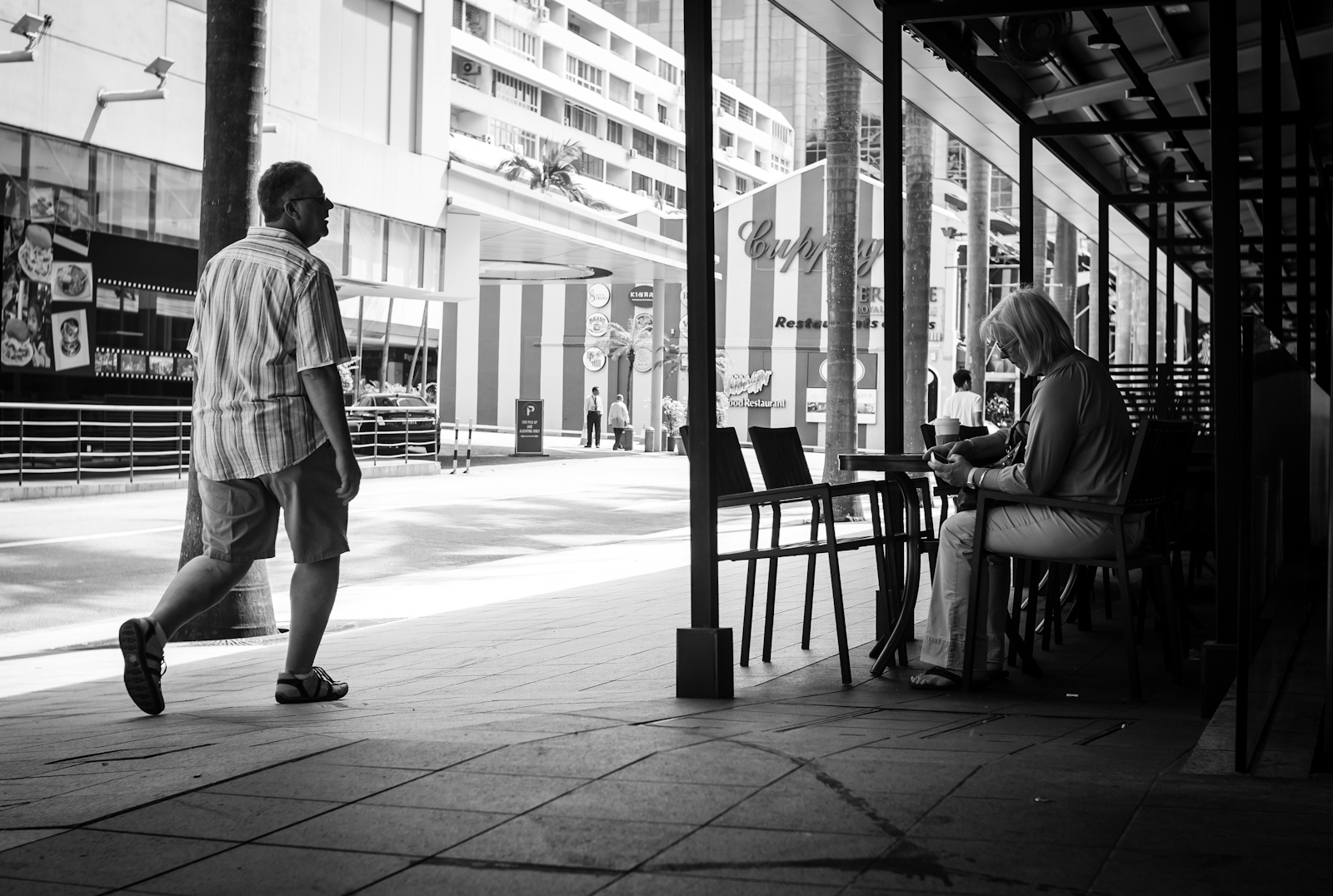 Street photography - man walking past a woman in Starbucks