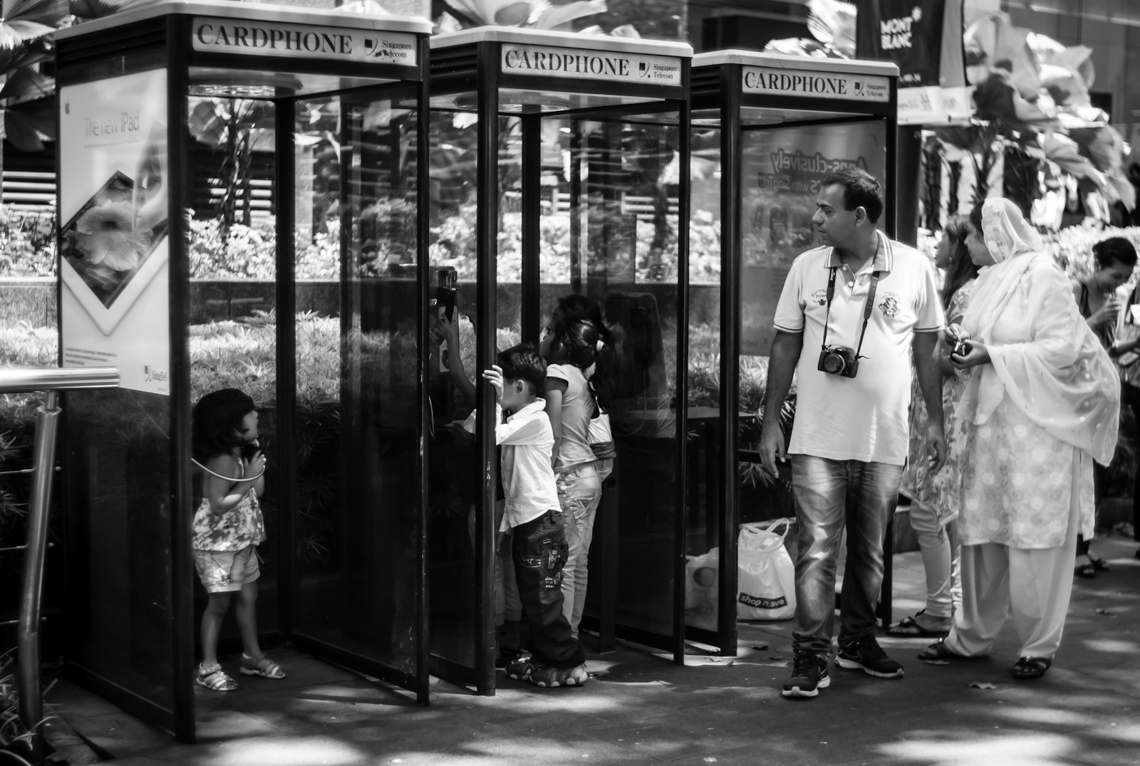Street photography - tourist family playing with a phone booth in Orchard Road
