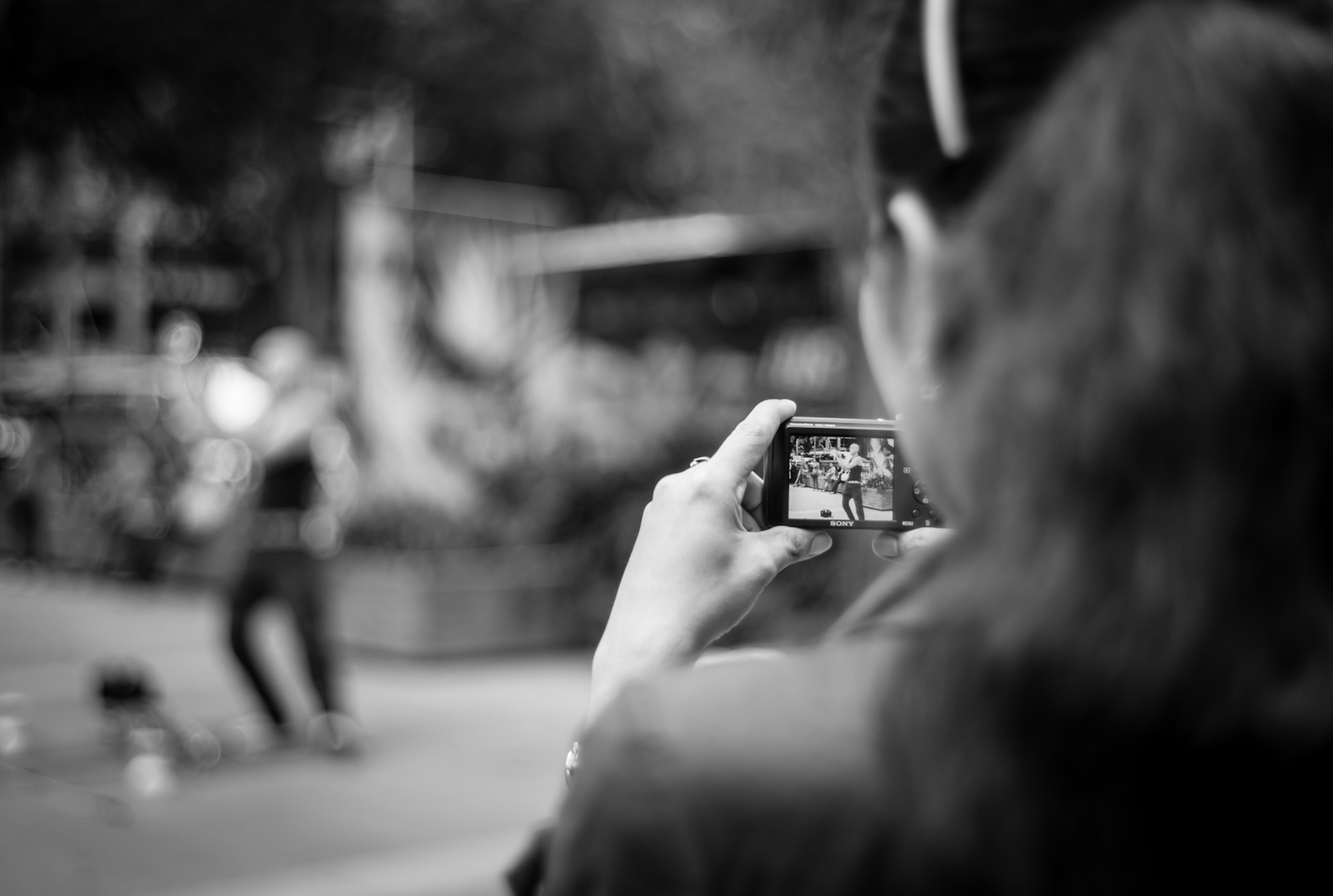 Street photography - Woman recording a video of a street performer