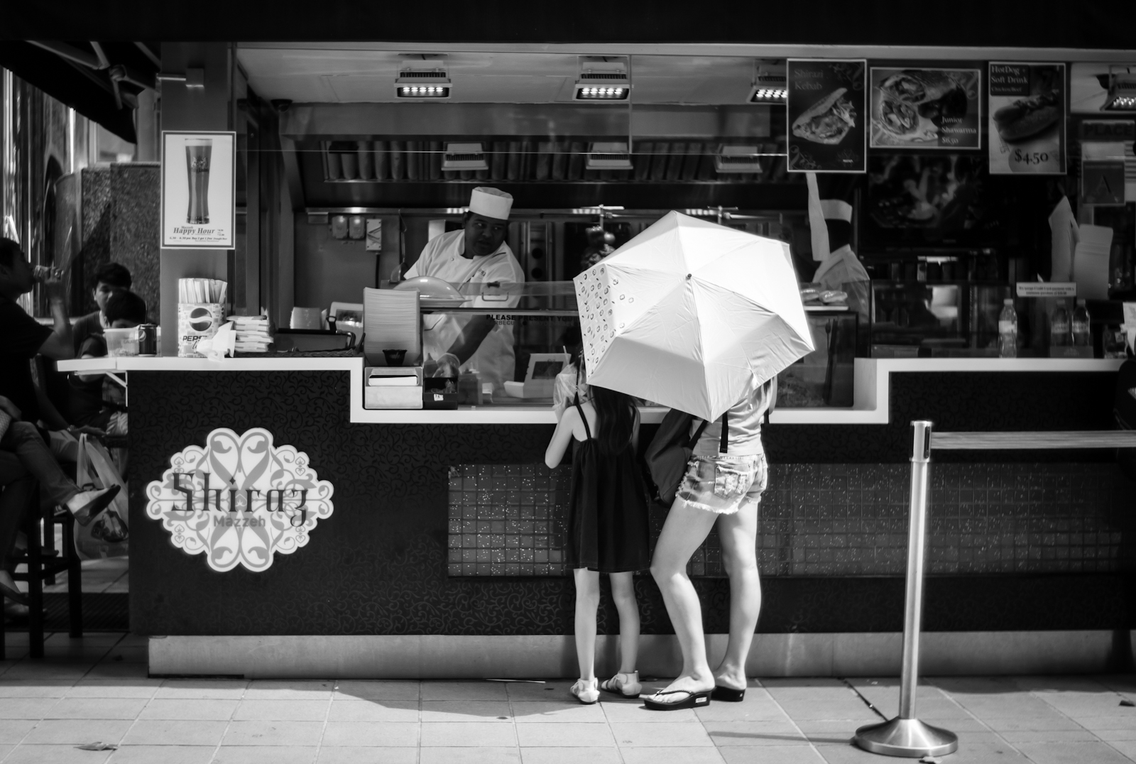 Mother and daughter standing beneath their umbrella while ordering food