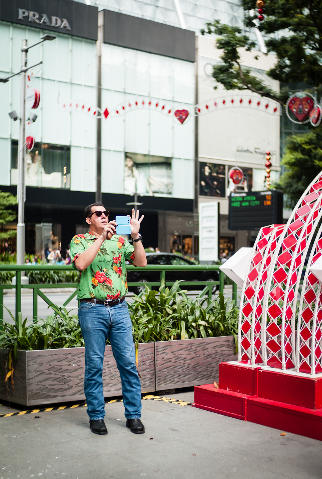 A man in bright clothing taking photos with his smartphone camera